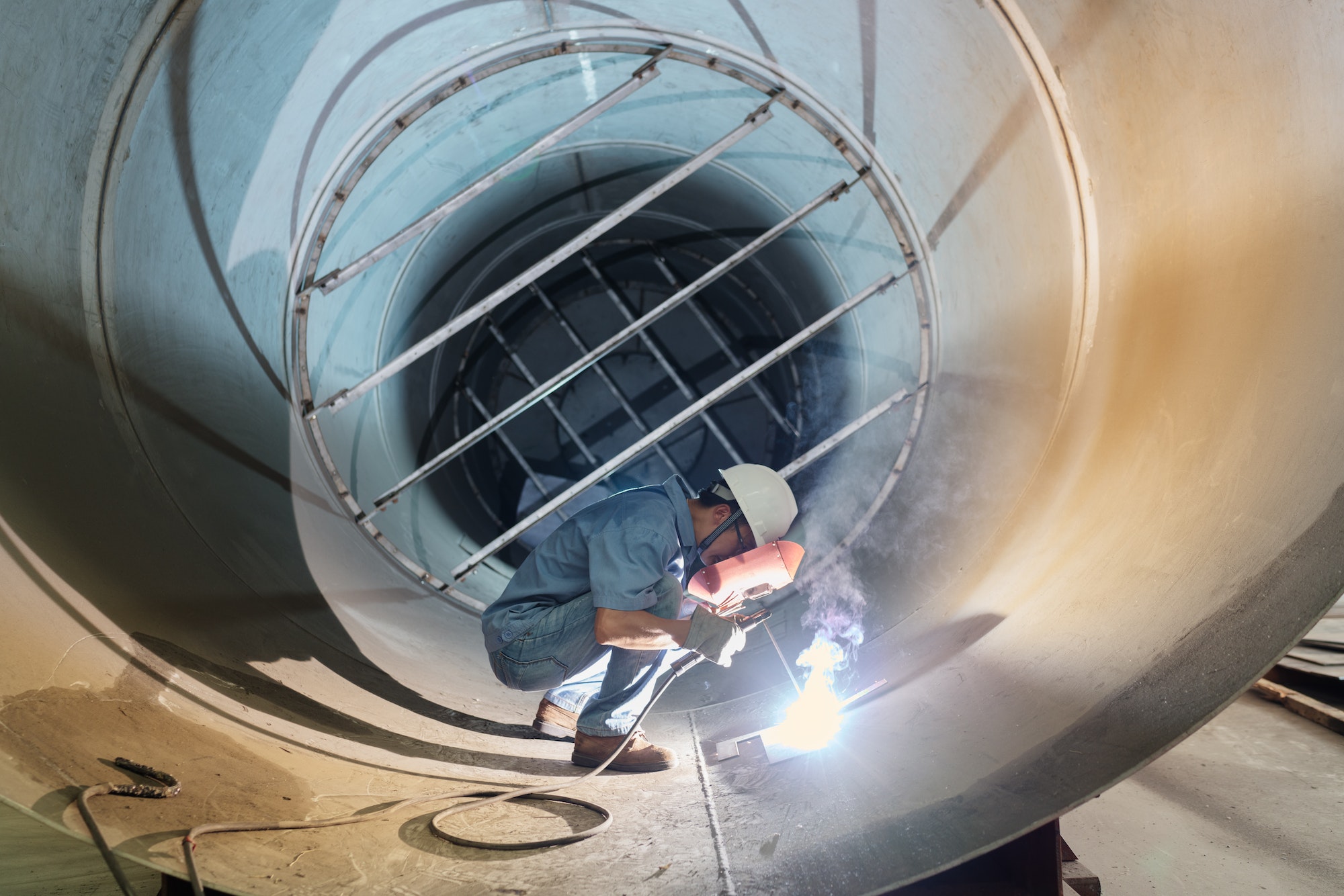 Male welder working in industrial pipe at crane factory, China